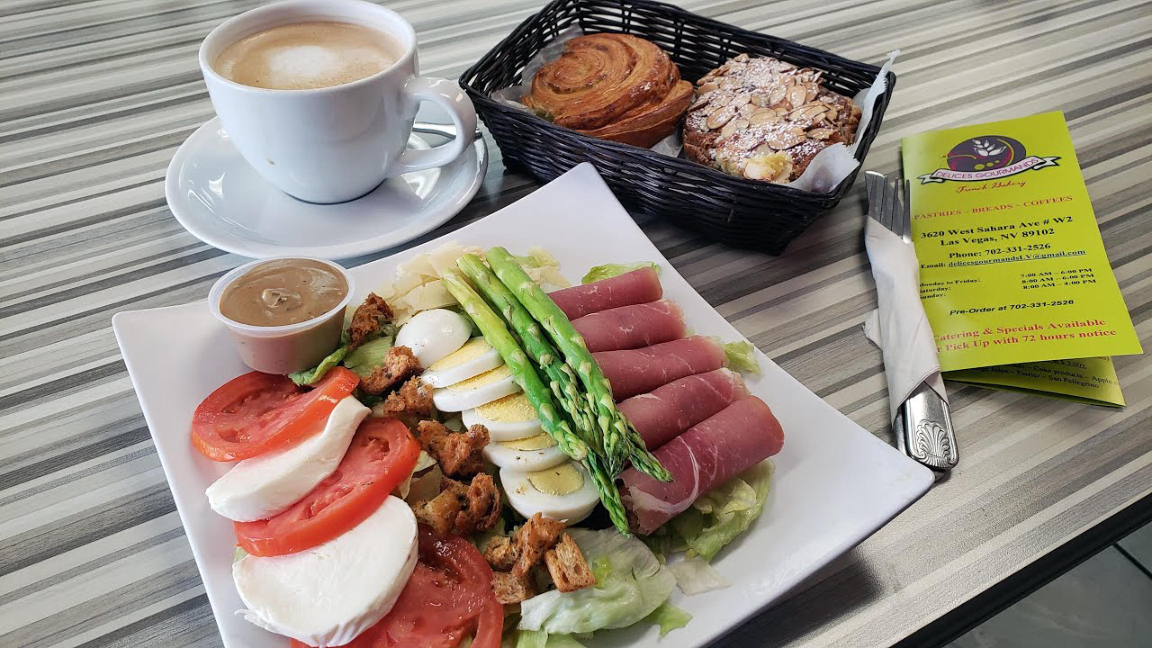 undefined Delices Gourmands French Bakery in Las Vegas serving a hefty plate of eggs, cheese, tomatoes, ham & lettuce for breakfast, paired with hot coffee & freshly baked breads